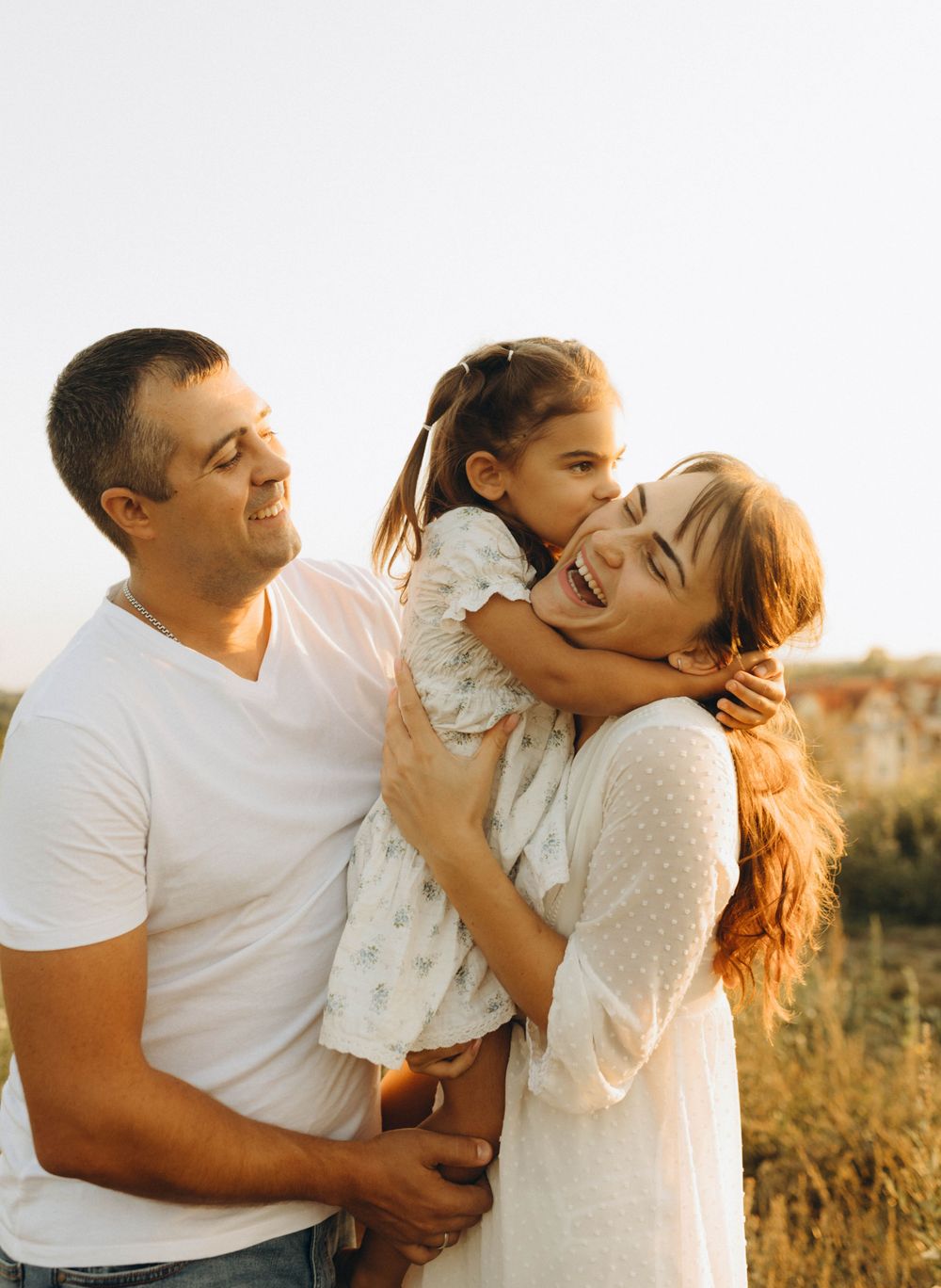 Parents embracing their young daughter outdoors